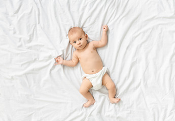 Adorable little baby lying on bed at home, top view