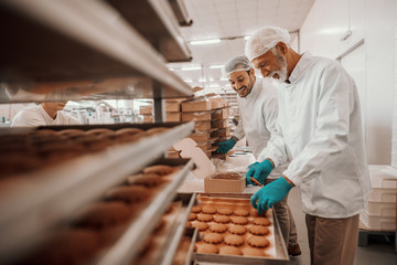 Two hardworking dedicated Caucasian employees dressed in white sterile uniforms collecting and...