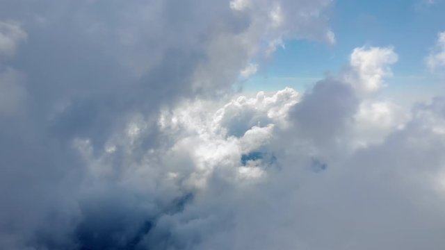 Flying through beautiful thick fluffy clouds. Amazing timelapse of soft white clouds moving slowly on the clear blue sky in pure daylight. Direct view from the cockpit.