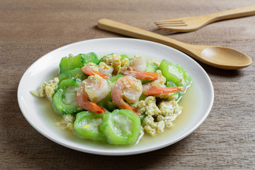 stir fried luffa with shrimp in a ceramic dish on wooden table. delicious and healthy homemade style food concept