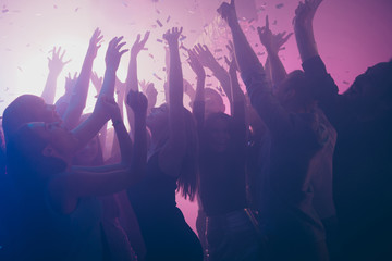 Close up photo of many festive excited people dancing clubbing purple lights confetti fog nightclub...