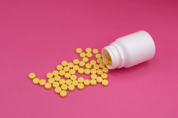 Pills and bottle on pink background