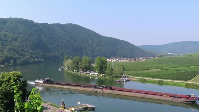industrial ship driving along moselle river with its vineyard landscape in Germany.