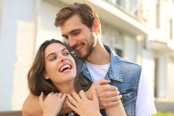 Handsome young man embracing his beautiful girlfriend while spending time together in the city.