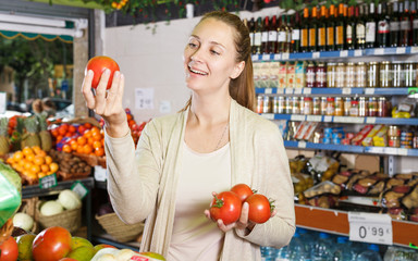 Smiling woman is choosing tomatos