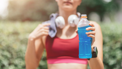 Cropped portrait of tired asian woman holding a bottle of water and a towel after workout session. Horizontal shot. Front view