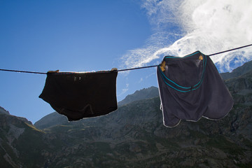 Two underpants, mens and womens, backlit, hanging from clothesline in the mountains