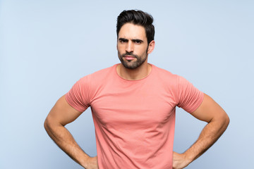 Handsome young man in pink shirt over isolated blue background angry