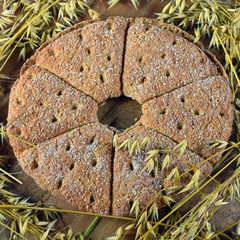 Top view of oat bread and oat ears of grain on wooden table. Square shape image.