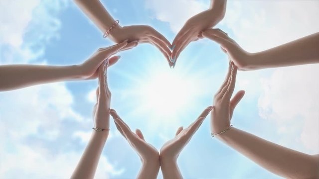 A group of youth makes a heart shape out of their hands.
