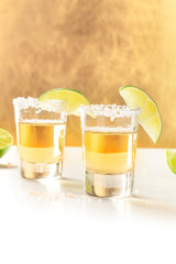Golden tequila shots with salt, lime slices, and a place for text