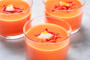 Salmorejo, Spanish cold tomato and bread soup, in glasses on a marble background, close-up shot