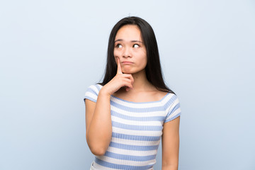 Fototapeta premium Teenager asian girl over isolated blue background thinking an idea