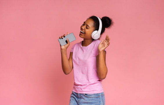 Happy African American Teen Singing Into Smartphone Like Microphone