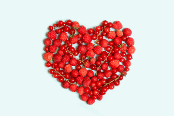 Heart shape assorted berry fruits on blue background.