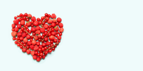 Heart shape assorted berry fruits on blue background.