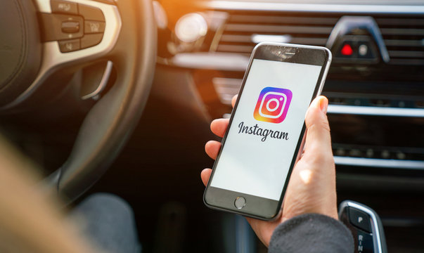 AACHEN, GERMANY AUGUST 2019: Woman holding a Apple iPhone opening Instagram app in a car. Instagram is a social media sharing plattform