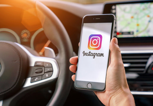 AACHEN, GERMANY AUGUST 2019: Woman holding a Apple iPhone opening Instagram app in a car. Instagram is a social media sharing plattform