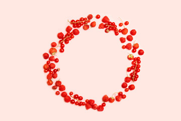 Food circle frame of red ripe currants, strawberries and raspberries with on a pink background. View from above. Flat lay