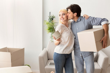 Man Kissing Wife Holding Moving Box Unpacking In New House