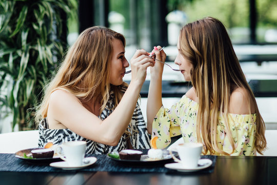 Cute emotions. Pretty mother and doughter feeds each other in mnodern cafe, while eating dessert.
