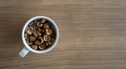 bowls with chocolate cornflakes and milk for breakfast on wooden table. top view