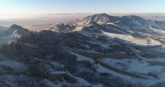 Aerial: Drone approaching snow covered mountains during winter against sky - Northern Countryside, Mongolia