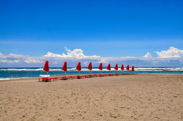 Closed red sun parasols on the beach at Frangokastello on the Greek island of Crete