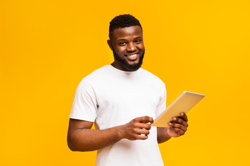 Smiling African American Guy Holding Digital Tablet Standing Indoors