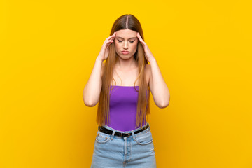 Young woman over isolated yellow background with headache