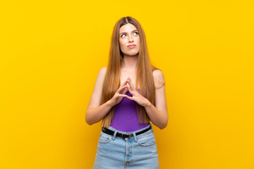 Young woman over isolated yellow background scheming something