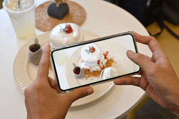Woman hands takes photography of dessert with phone. Pancake and strawberry with cream. mobile photo for post on social networks.
