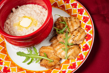 Bowl with prepared oatmeal with butter and chicken fillet