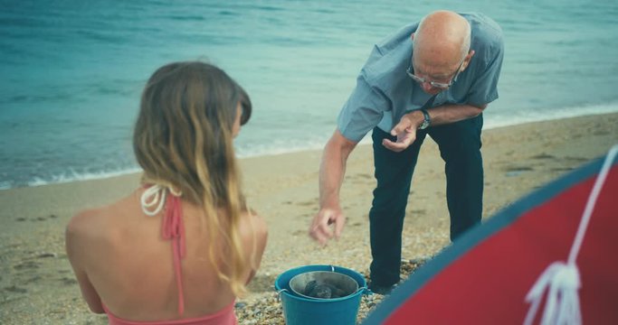 Young woman having barbecue on the beach with her father
