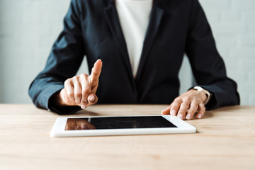 cropped view of woman pointing with finger at digitla tablet with blank screen on table
