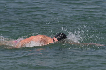 Person swimming freestyle in the see in marathon competition