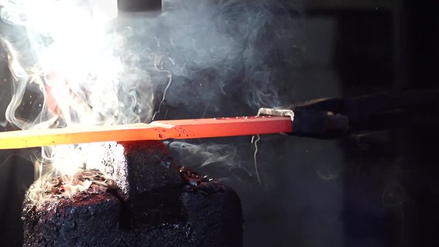 Blacksmith forges smoking steal on industrial hammer. close up dolly left slow motion 240fps