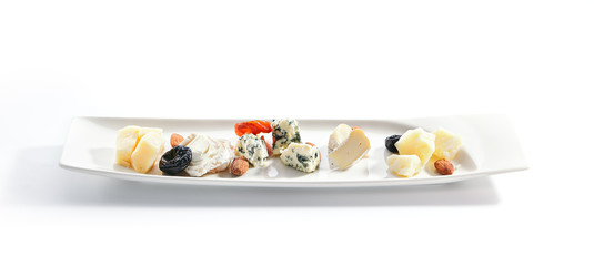 Cheese assorti platter closeup. Gorgonzola, brie, parmesan and chevre slices. Cow and goat milk chopped cheese on plate. Served delicious snacks composition isolated on white background