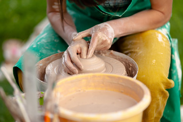 Hand craft making pottery on wheel. Female hands mold ceramic plate from clay (pot).