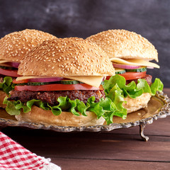 burger with fried cutlet, cheese and vegetables in a round wheat flour bun