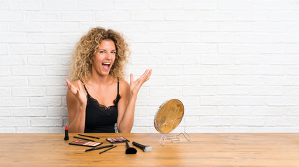 Young woman with lots of makeup brush in a table unhappy and frustrated with something