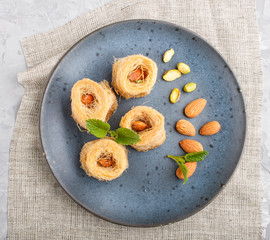Kunafa, traditional arabic sweets in blue ceramic plate on a gray concrete background. top view.