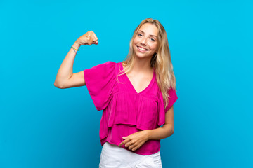 Fototapeta premium Blonde young woman over isolated blue background doing strong gesture