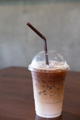 Iced coffee in plastic cup on wooden table