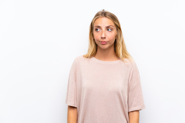 Blonde young woman over isolated white background standing and looking to the side