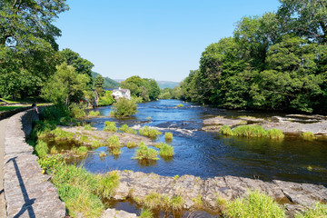 Fototapeta na wymiar Beside the fast flowing water of the River Dee in Llangollen, Wales in bright summer sunshine.