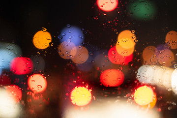 Close up windshield raindrop heavy rain with bokeh of traffic light ,Driving car on the road in traffic jam in rainy season