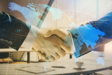 Multi exposure of world map on office background with two businessmen handshake. Concept of international business