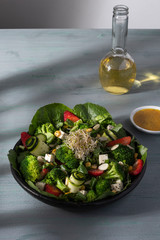 Ensalada de lechuga romana con fresas, queso, pepino y hierbas chicas vista desde arriba sobre mesa desgastada en grises. 