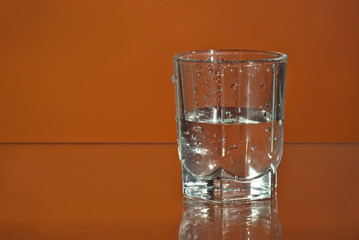 Alcoholic drink in clear glasses. Little cups isolated on orange background. Frozen drinks on glass table.